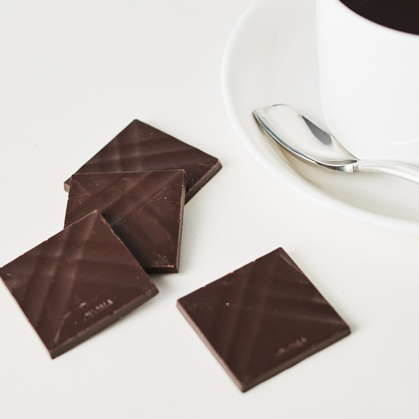A photo of the sugar free dark chocolate next to a cup of coffee